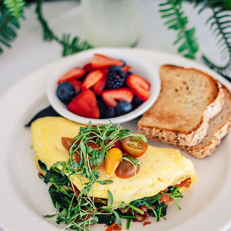 Omlete on a plate with a side of toast and fresh fruit.