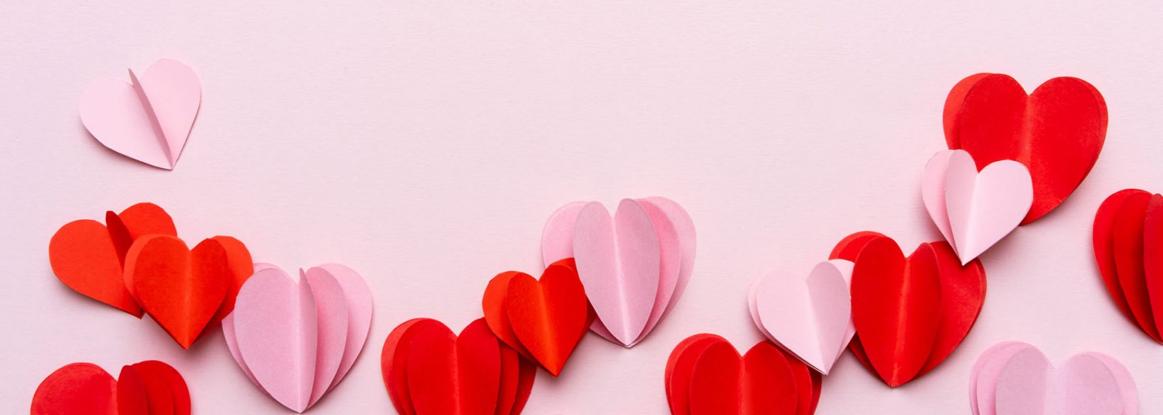 Red and pink paper hearts on a pink background