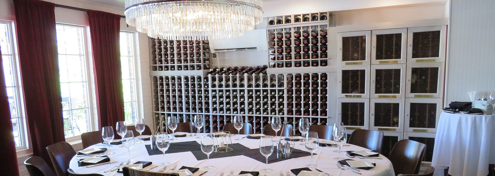 Table for 12 set in wine cellar room with wine lockers.