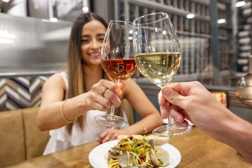Woman clicking glass of wine with her guest.