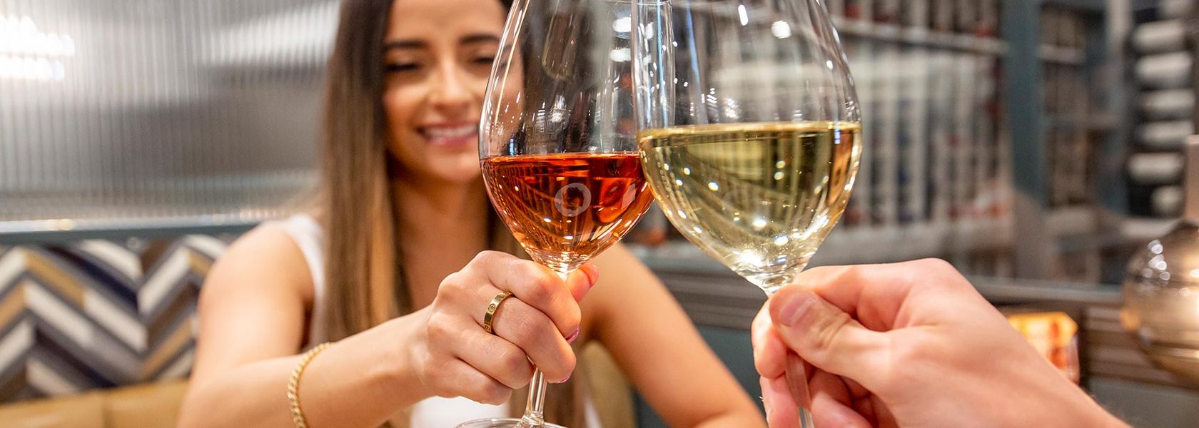 Woman clinking wine glasses in toast with dining companion.