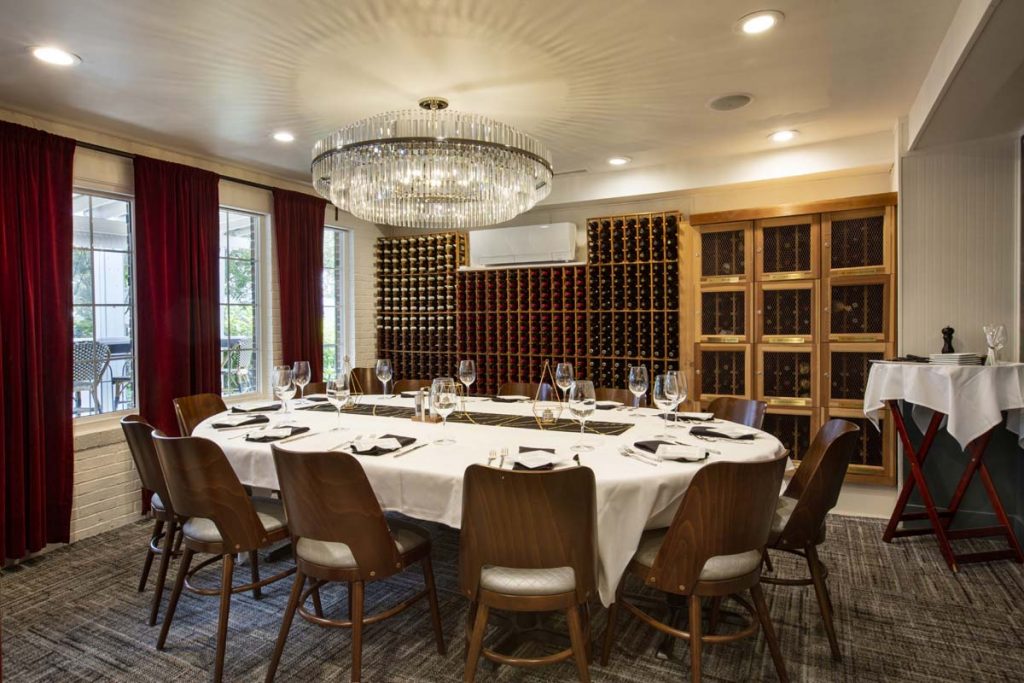 Private dining room with wine cellar on one wall and service set for 12 on center table