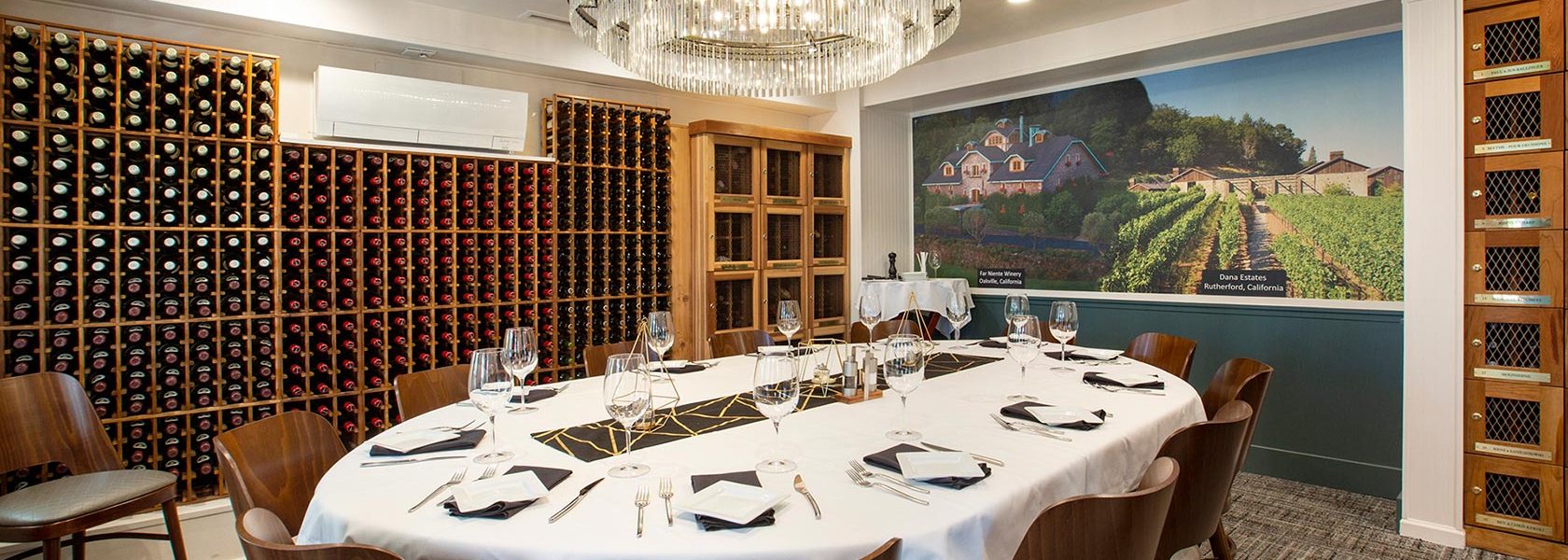 Private dining room lined with wine racks and wine lockers, table set for service for 12.