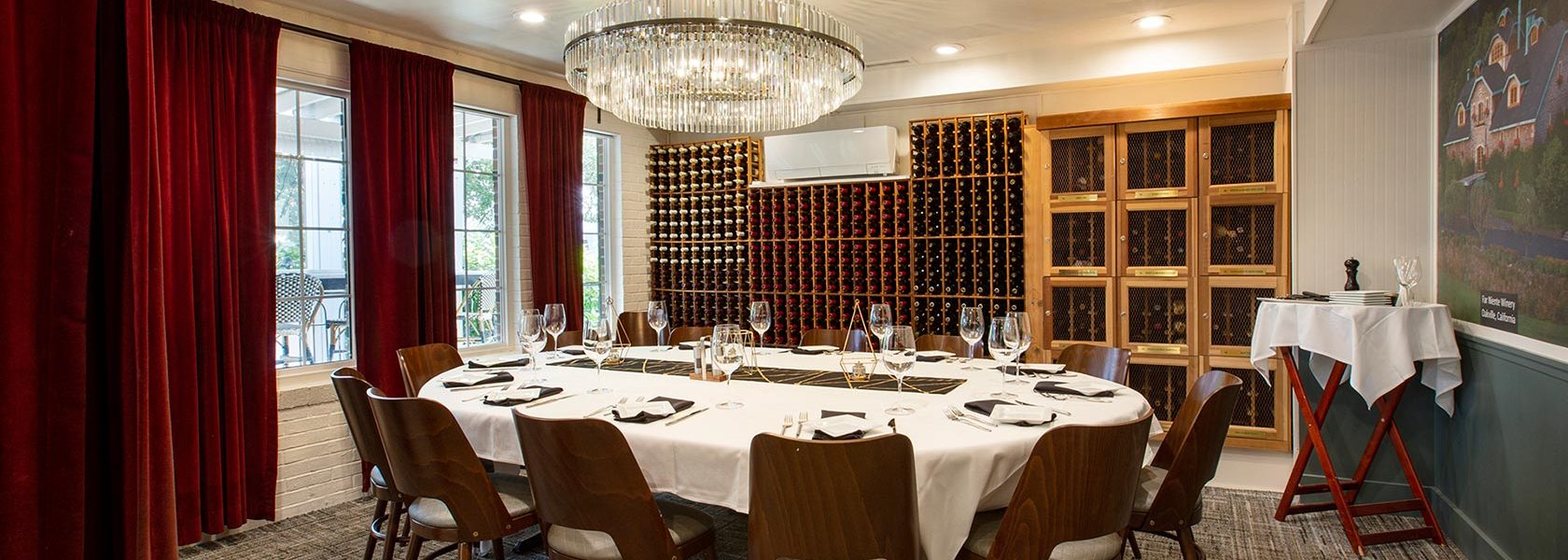Private dining room and wine cellar with service set for 12 at oval table.