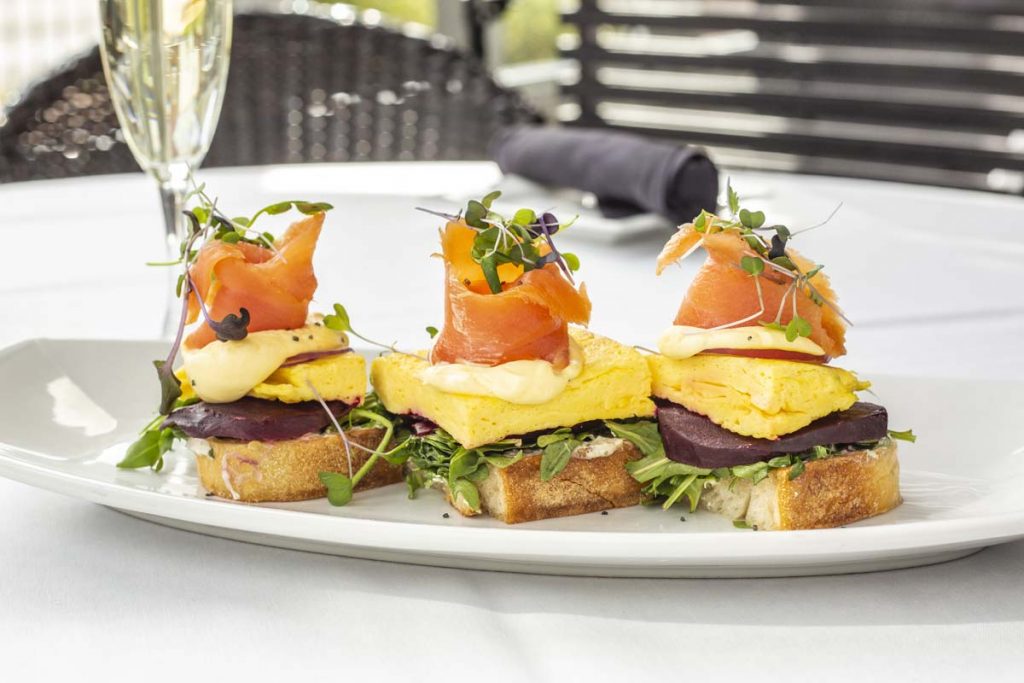 Tucci’s Smoked Salmon Toast brunch entree with thin slices of smoked salmon on scrambled egg and watercress on toast