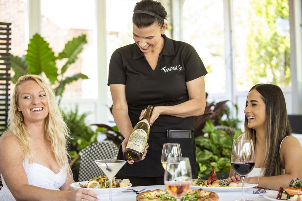 Tucci’s server presents wine bottle to guest for approval