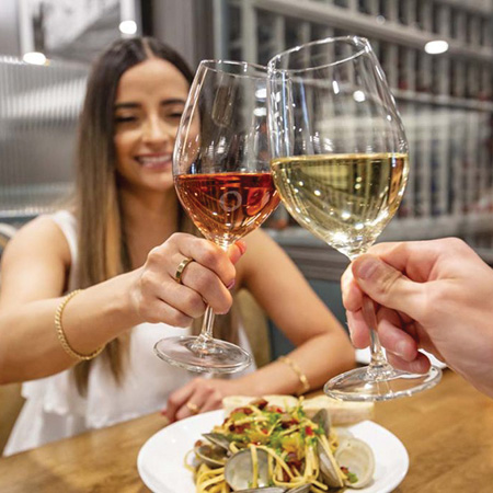Smiling woman clinking wine glass above entree