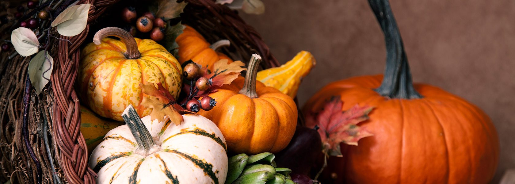 Beautiful arrangement of fall gourds and pumpkins in woven horn of plenty.