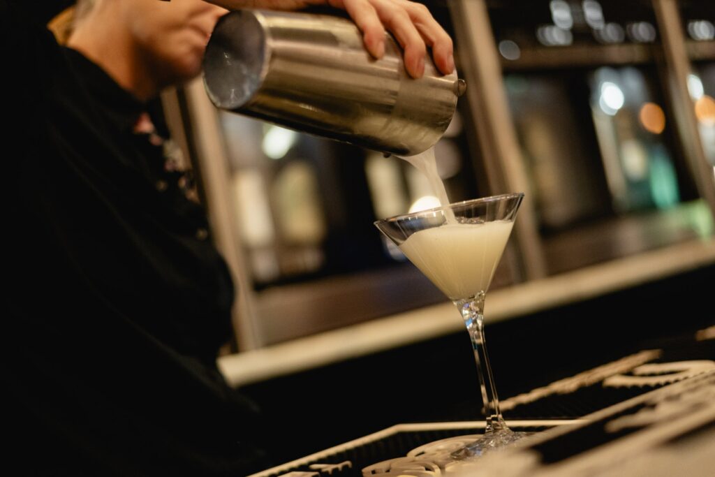 A bartender pouring a martini at Tucci's bar