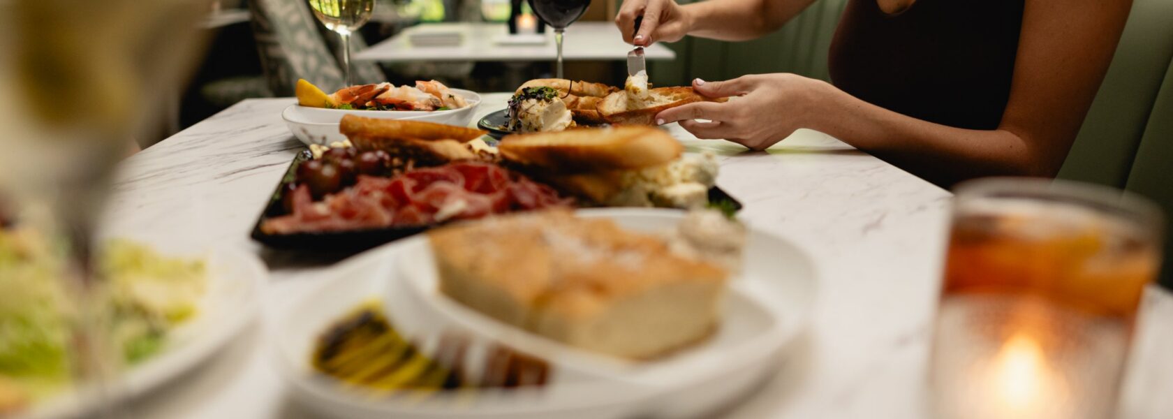 A shared table at Tucci's with rosemary focaccia, charcuterie and cocktails